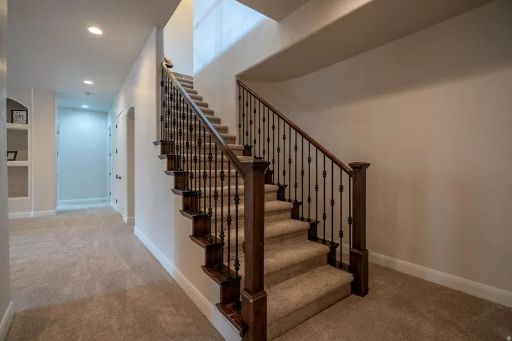 Staircase featuring dark wood handrails and newel posts with wrought iron balusters