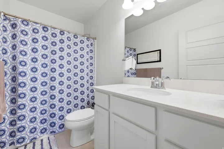 Bathroom featuring a single vanity with stone-finish countertop, undermount sink, and chrome faucet
