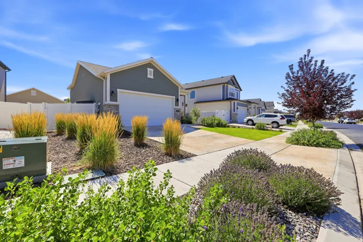 Modern single-family residence featuring a two-car garage, partial stone facade, and a white privacy fence