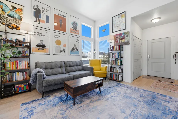 Bright living area featuring wood-finish flooring, tall windows, a built-in shelving unit, and a neutral entry door with hardware