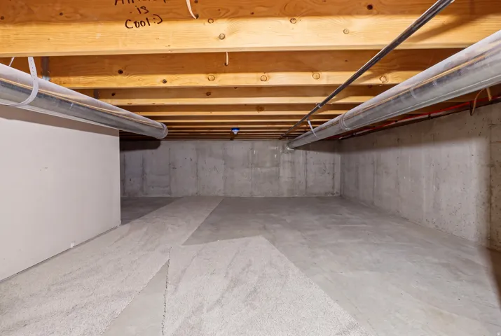 Unfinished basement with exposed wood joists and concrete flooring