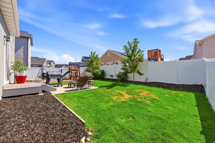 Expansive backyard featuring a manicured lawn, a gray composite deck, a concrete patio, and a white vinyl privacy fence