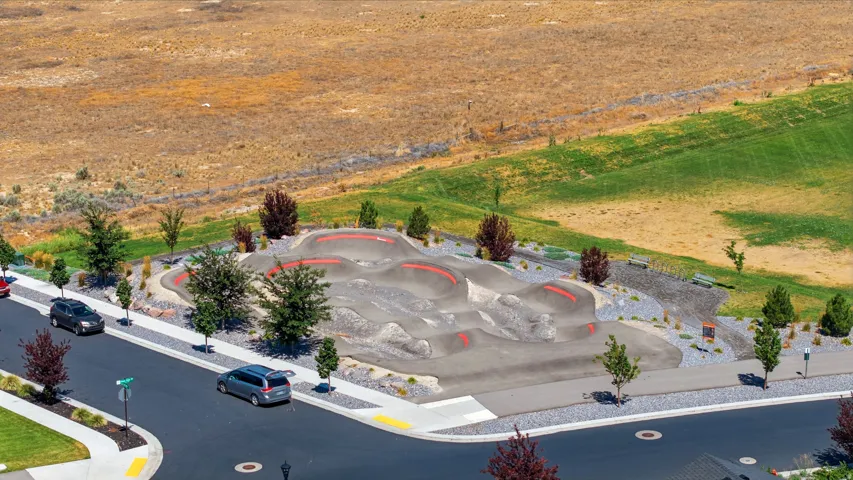Neighborhood pump track featuring sculpted terrain and integrated red-lined pathways
