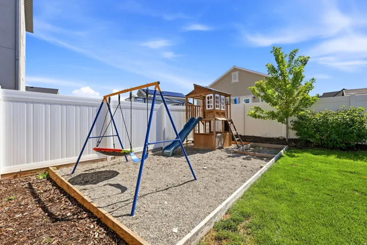 Expansive backyard featuring a lush lawn and a dedicated play area with a swingset and playhouse