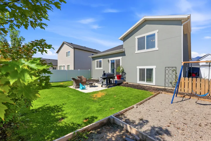 Expansive backyard featuring a manicured lawn, concrete patio, and mature tree