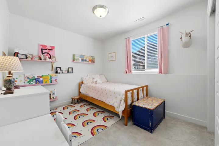 Carpeted room with a single window featuring blinds and pink drapes