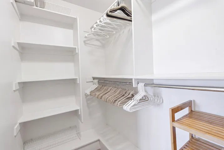 White built-in shelving system featuring multiple storage tiers and chrome hanging rods
