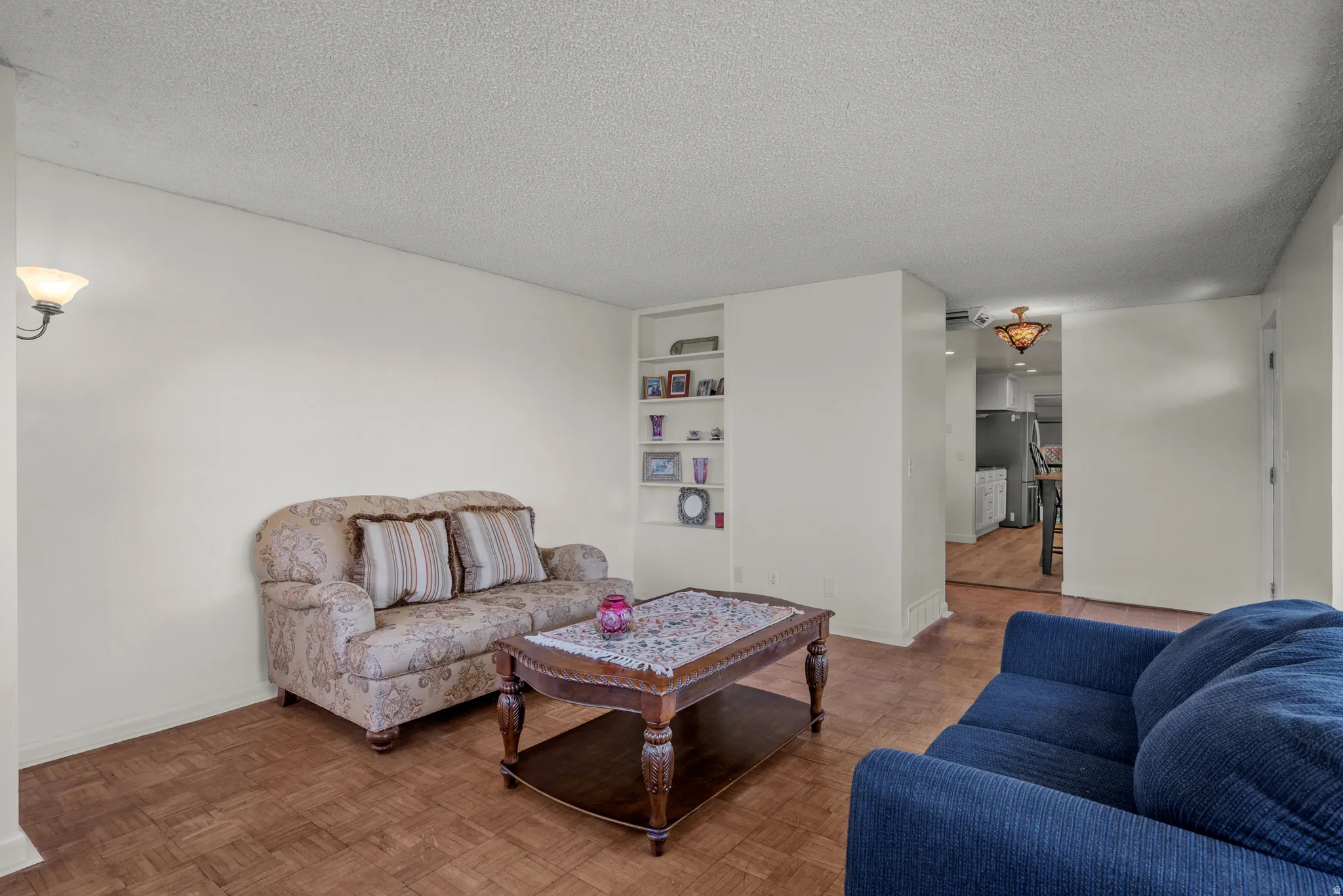 Living area featuring wood-finish flooring, built-in shelving, and a wall sconce