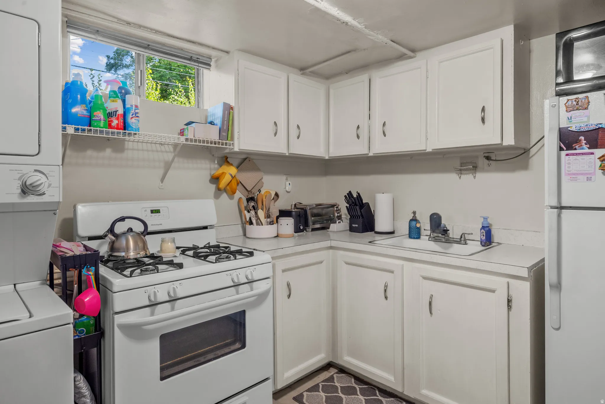 Kitchenette featuring white cabinetry, a white gas range, and a white refrigerator