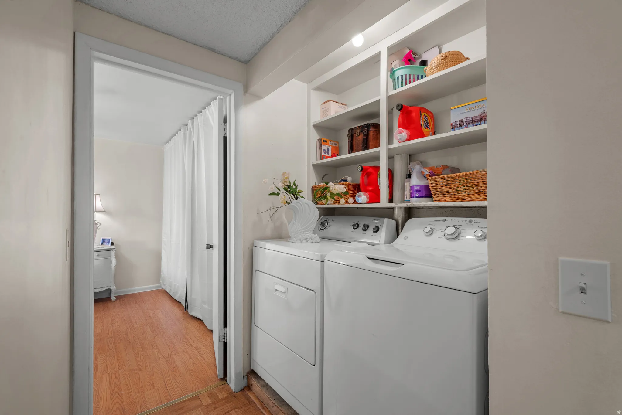 Dedicated laundry area featuring white appliances and integrated shelving