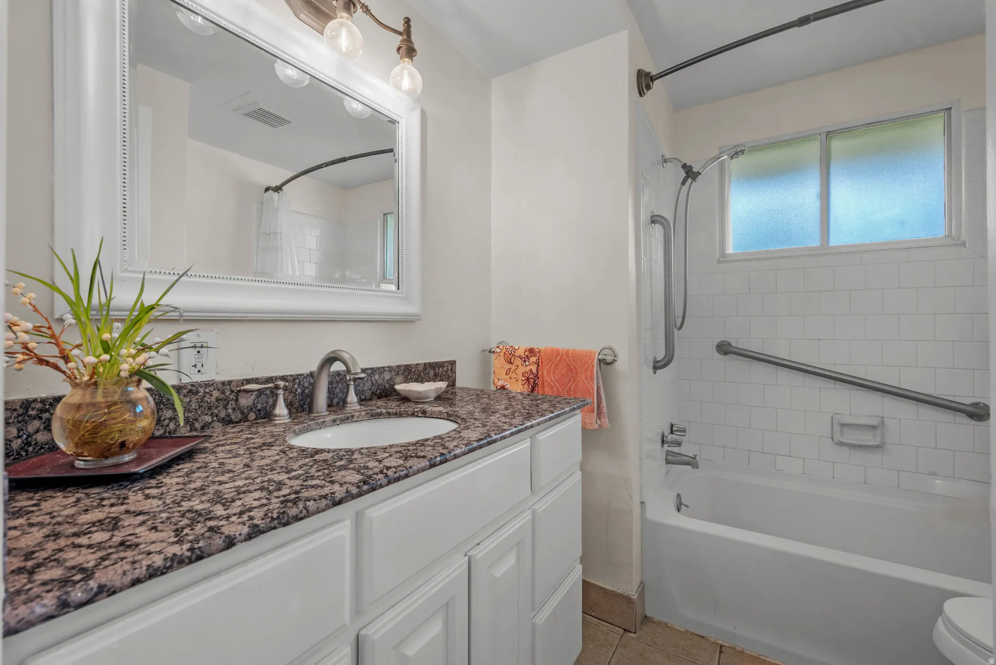 Bathroom featuring a white vanity with a dark granite-style countertop and an undermount sink
