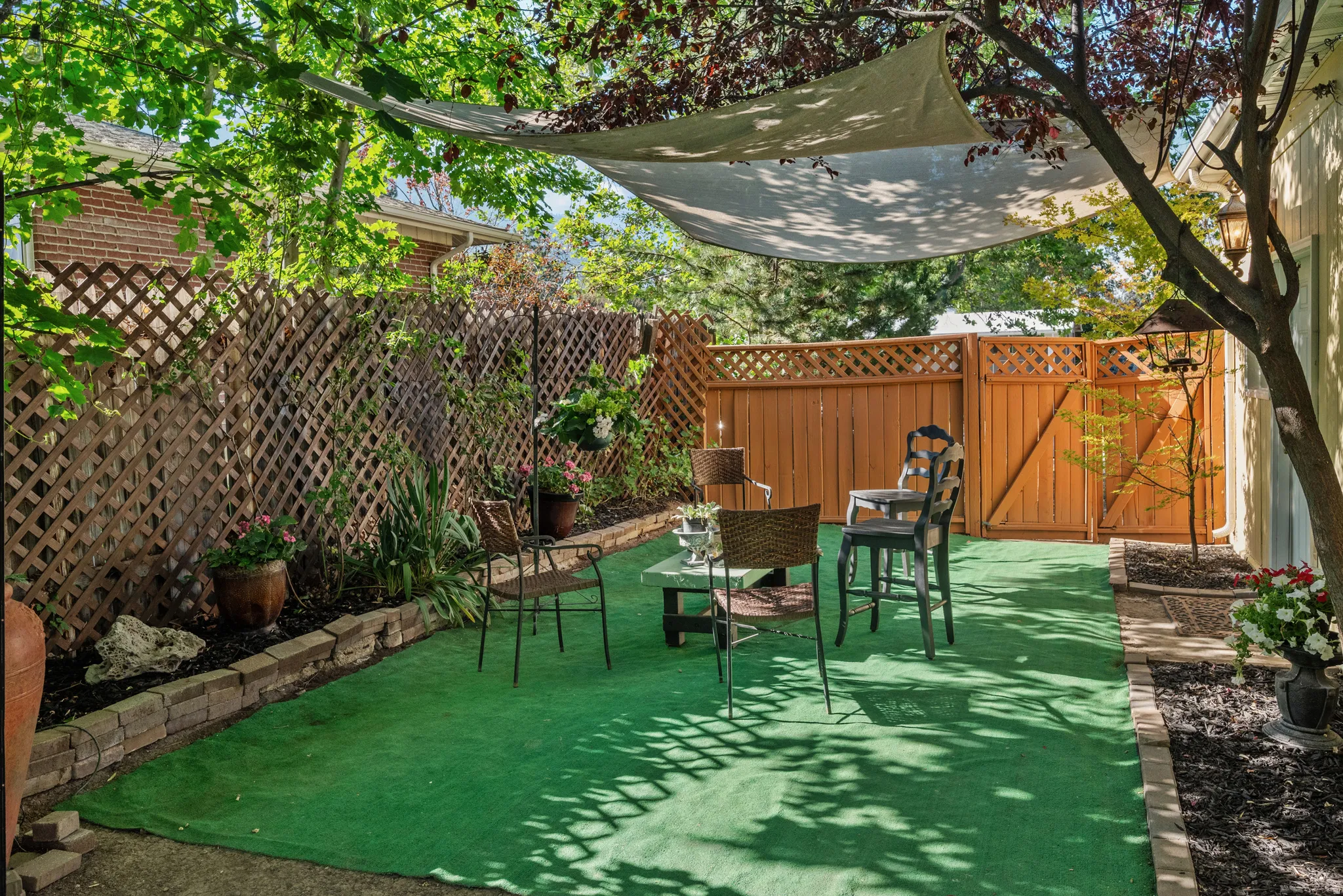 Private outdoor patio space featuring a shade sail and artificial turf