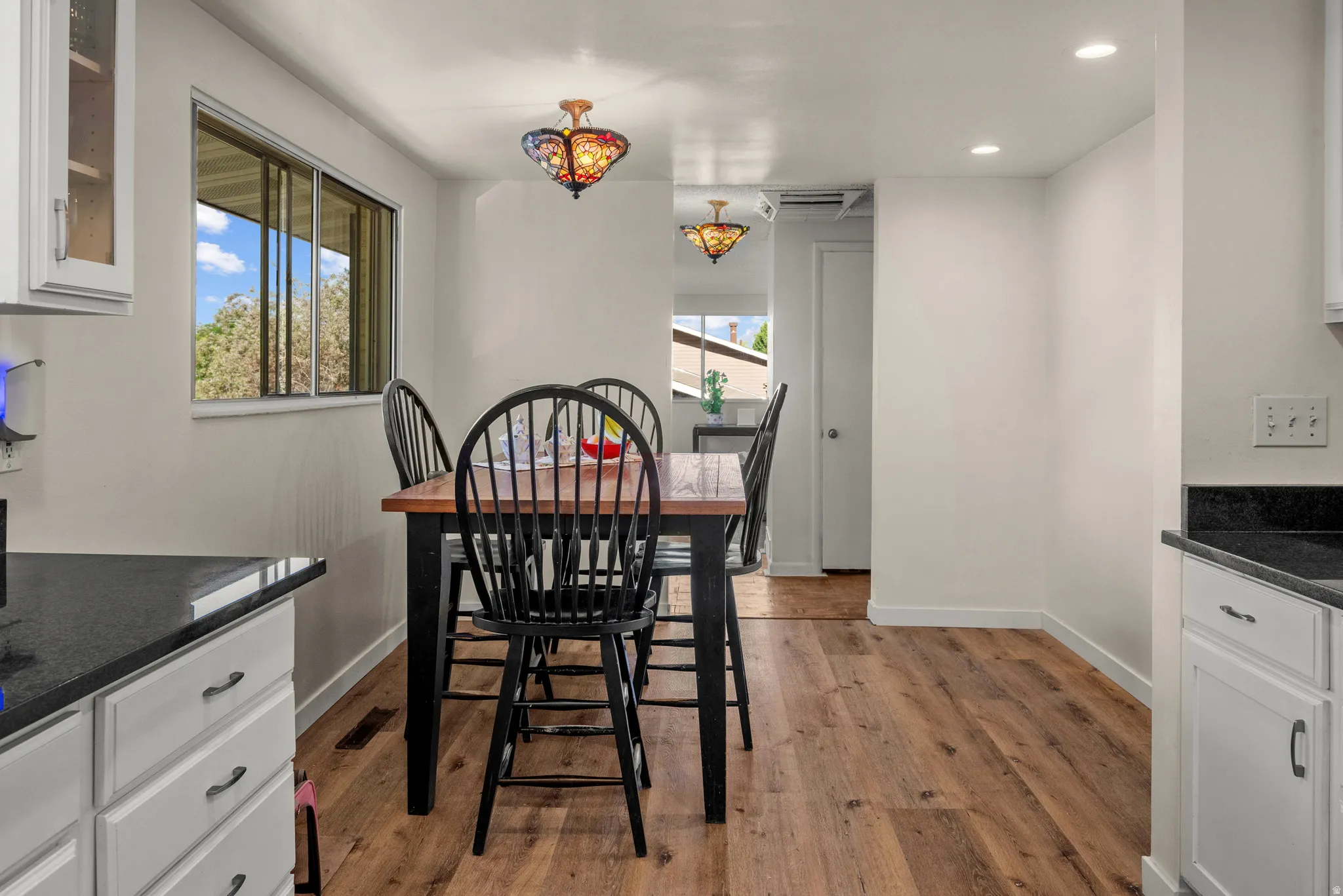 Dining area with wood-finish flooring, white walls, and a window with exterior views