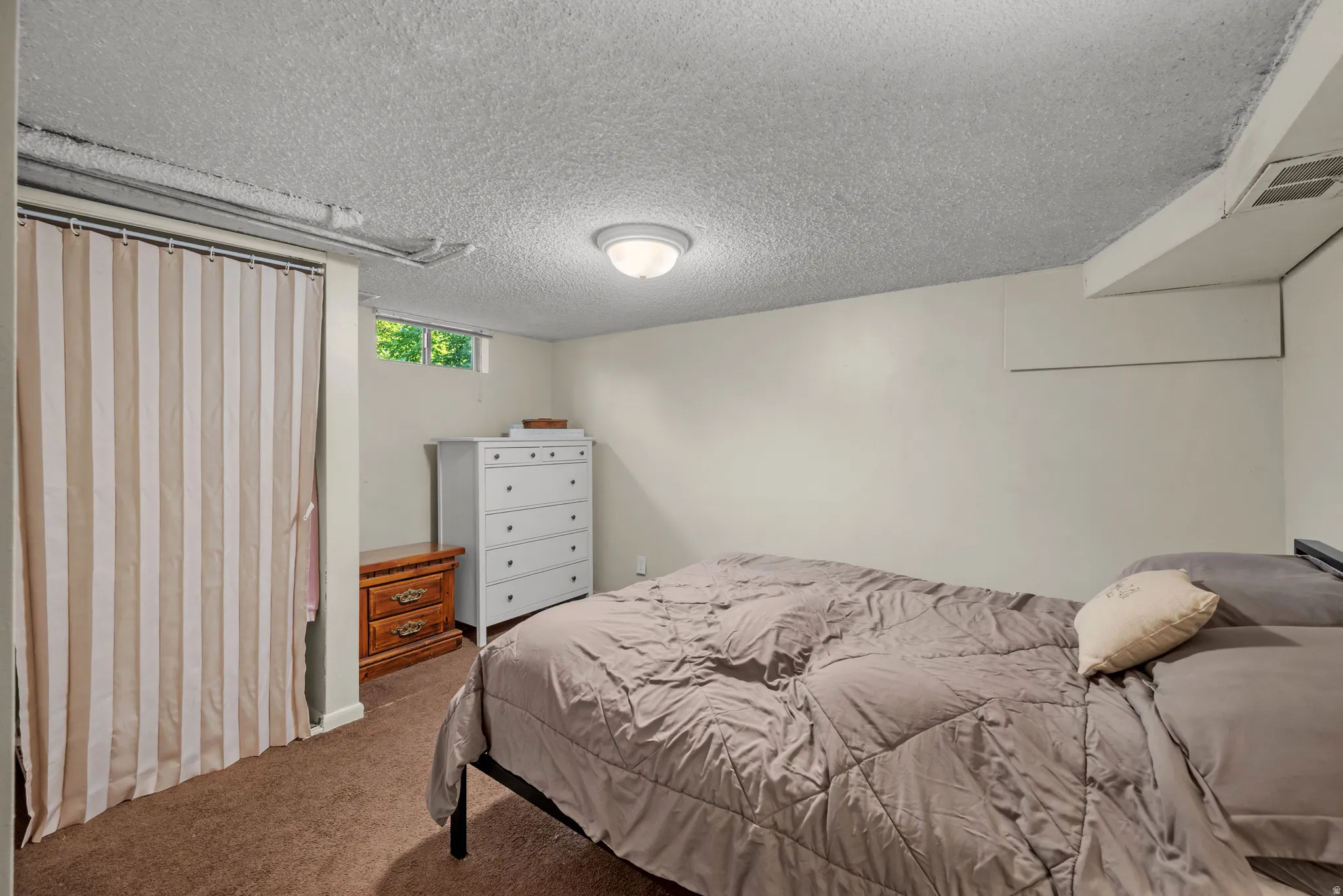 Carpeted interior space featuring white painted walls and a textured ceiling