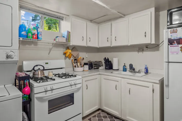 Kitchenette featuring white cabinetry, a white gas range, and a white refrigerator