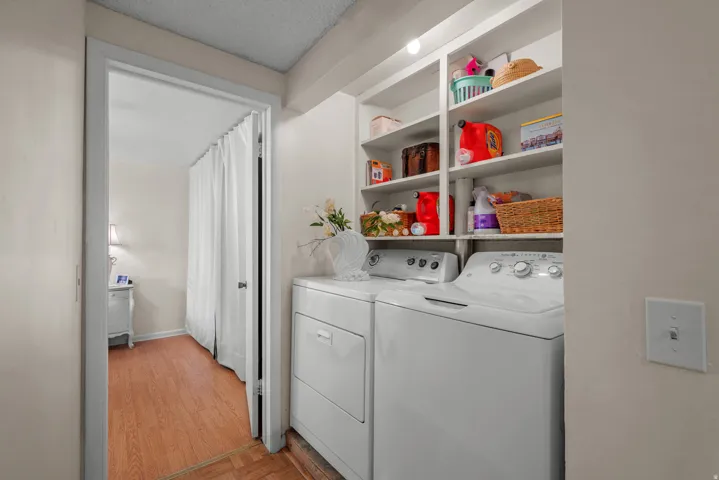Dedicated laundry area featuring white appliances and integrated shelving