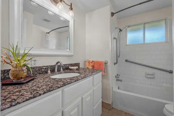 Bathroom featuring a white vanity with a dark granite-style countertop and an undermount sink