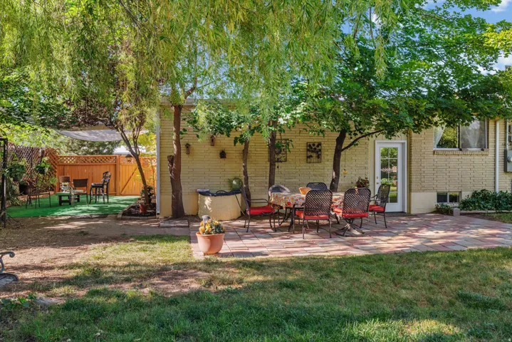 Expansive backyard featuring a brick paver patio, mature trees, and a wooden privacy fence