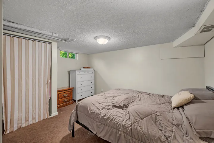 Carpeted interior space featuring white painted walls and a textured ceiling