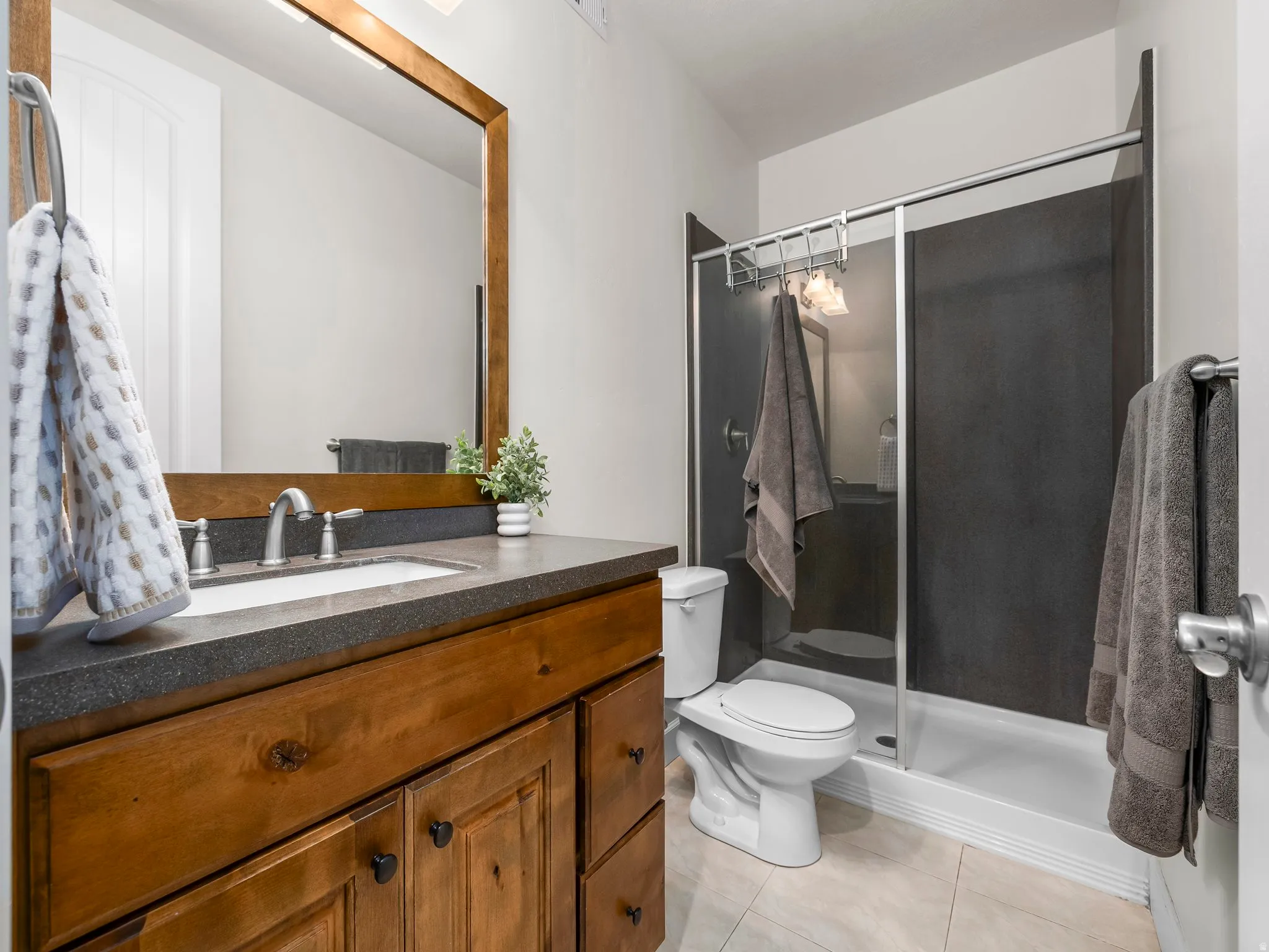 Bathroom featuring a wood-finish vanity with a dark countertop and undermount sink