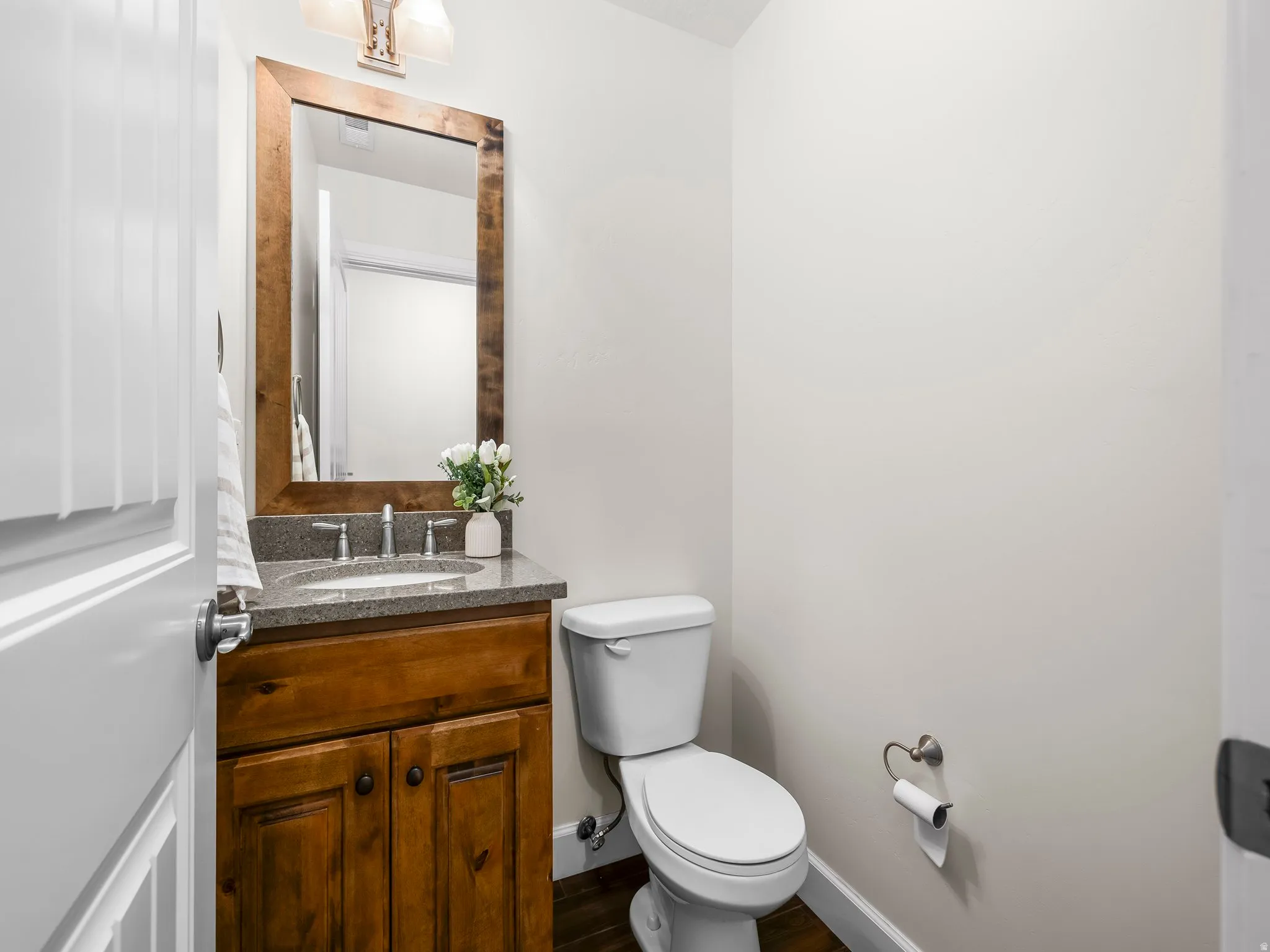 Vanity featuring a wood-finish cabinet, stone countertop, and an undermount sink with a brushed nickel faucet