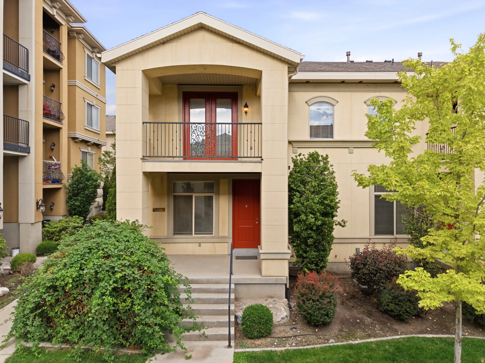 Stucco exterior residence featuring a second-story balcony with decorative iron railing