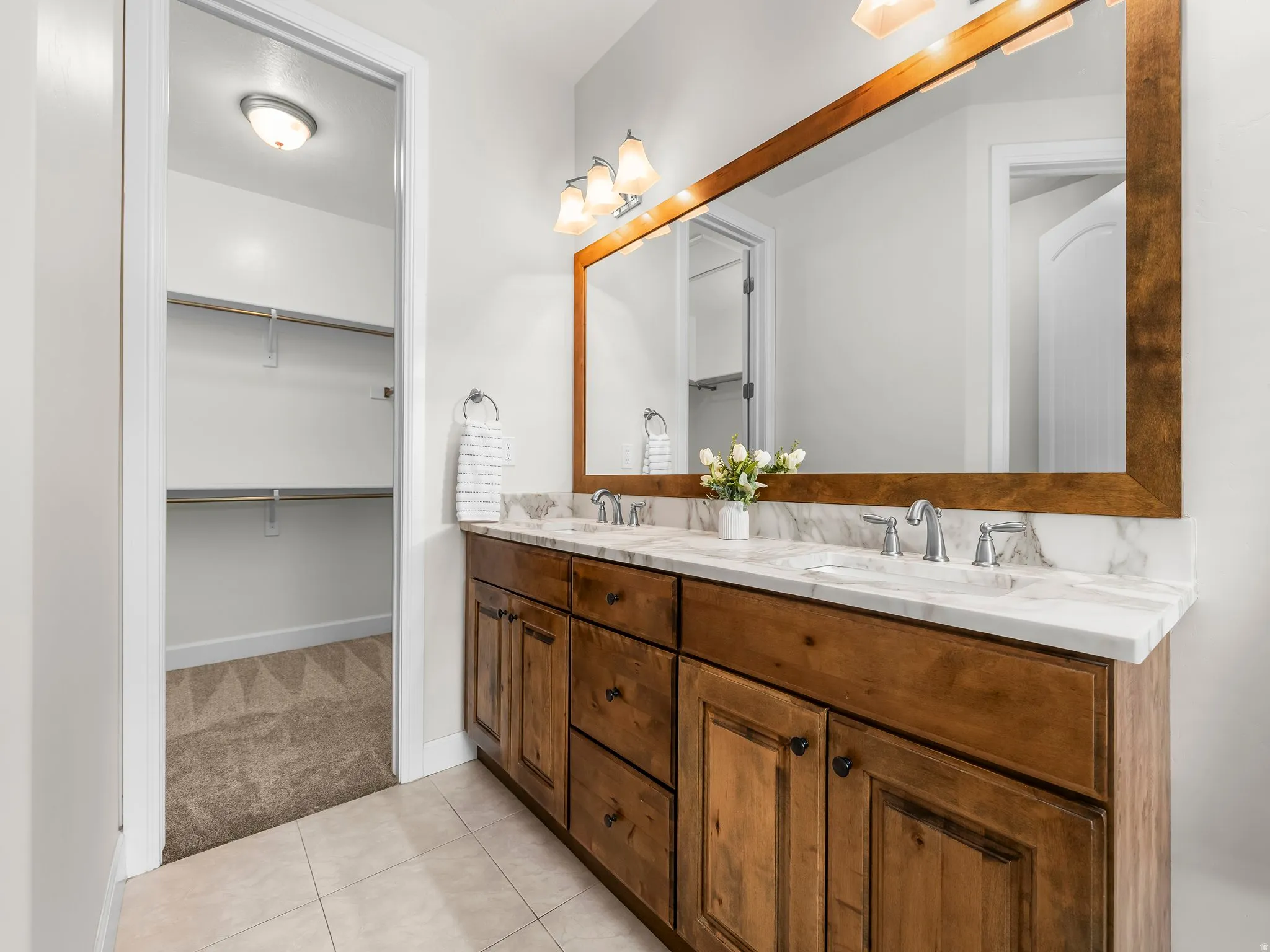 Bathroom featuring a dual vanity with a wood cabinet, white countertop, and individual sinks
