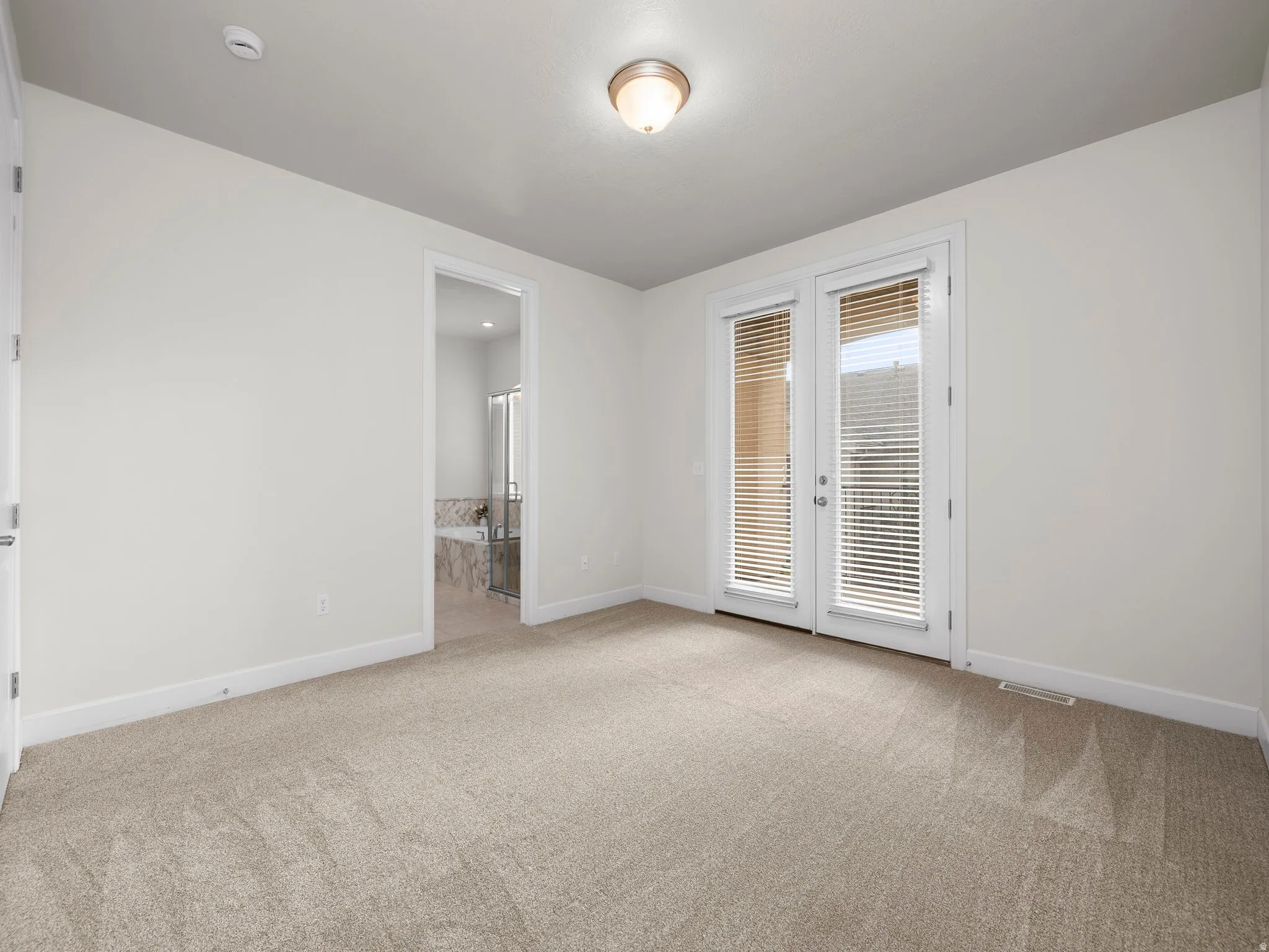 Neutral-toned carpeting extends throughout this room, featuring a white trim baseboard
