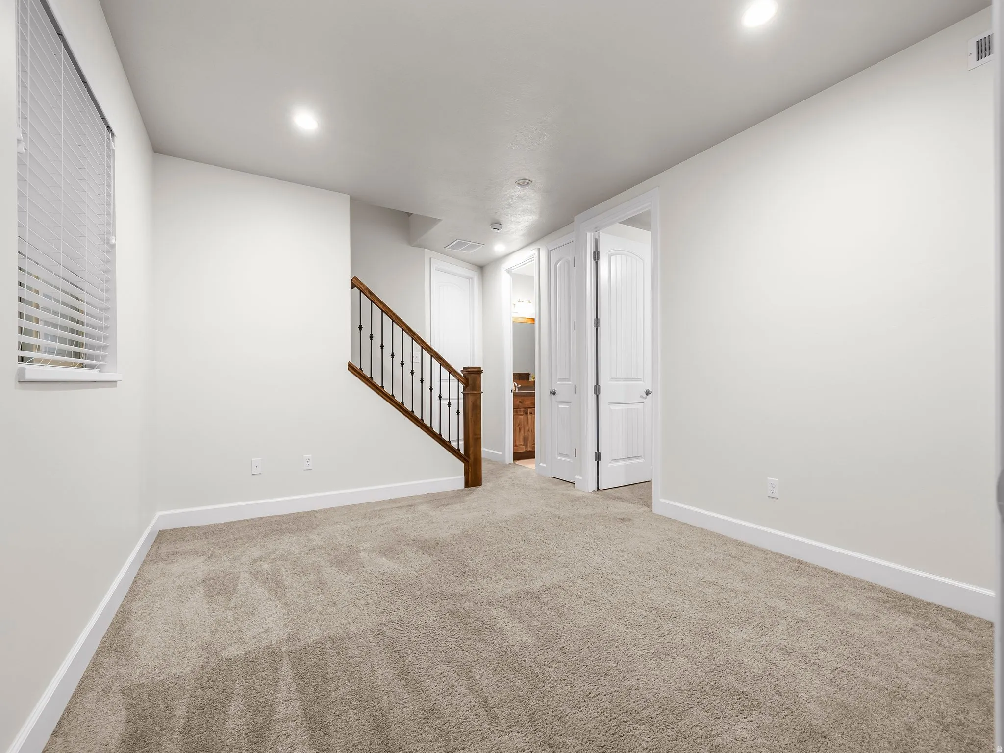 Carpeted room with recessed lighting, a window with blinds, and white baseboards