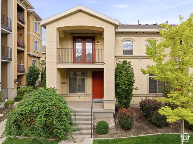 Stucco exterior residence featuring a second-story balcony with decorative iron railing
