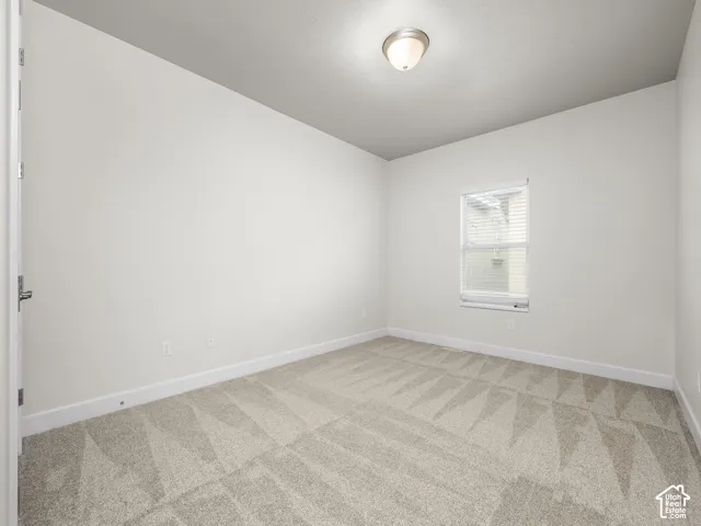 Carpeted room featuring a single window with blinds, white baseboards, and a flush mount ceiling light