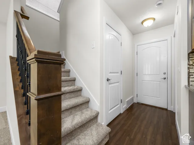 Entryway featuring wood-finish flooring, a white paneled door, and a staircase with wood newel post and baluster details