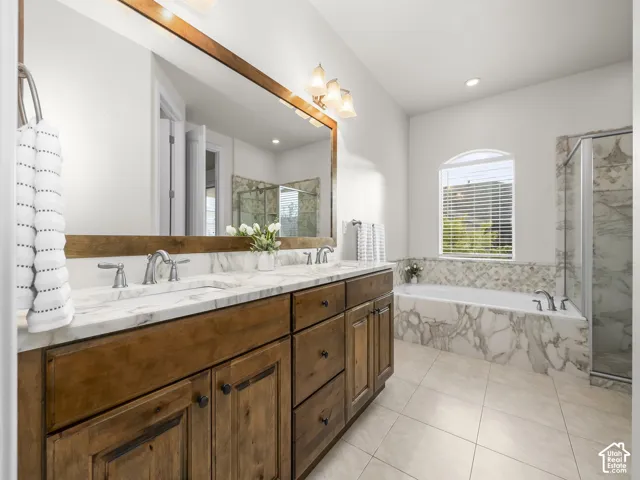 Bathroom vanity featuring a dual sink with a white stone countertop, warm wood-finish cabinetry, and a large framed mirror