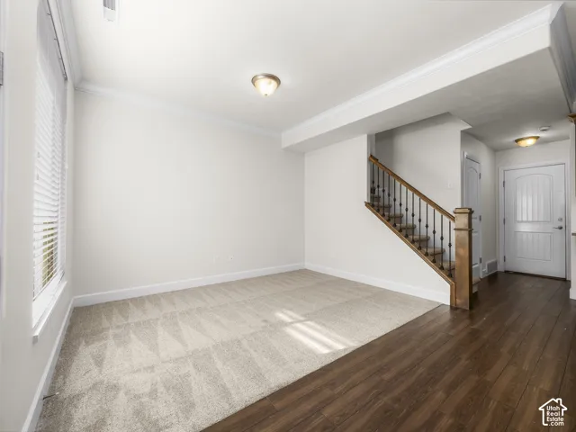 Open concept living area with light beige carpeting and crown molding