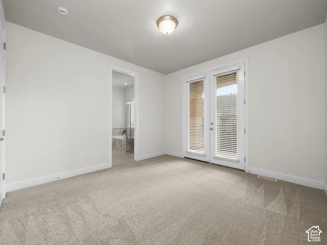 Neutral-toned carpeting extends throughout this room, featuring a white trim baseboard