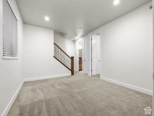 Carpeted room with recessed lighting, a window with blinds, and white baseboards