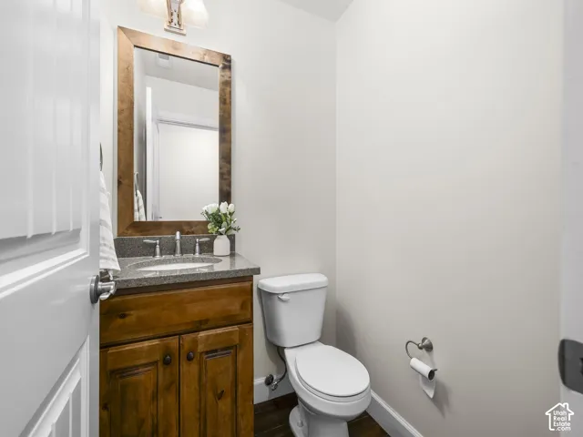 Vanity featuring a wood-finish cabinet, stone countertop, and an undermount sink with a brushed nickel faucet