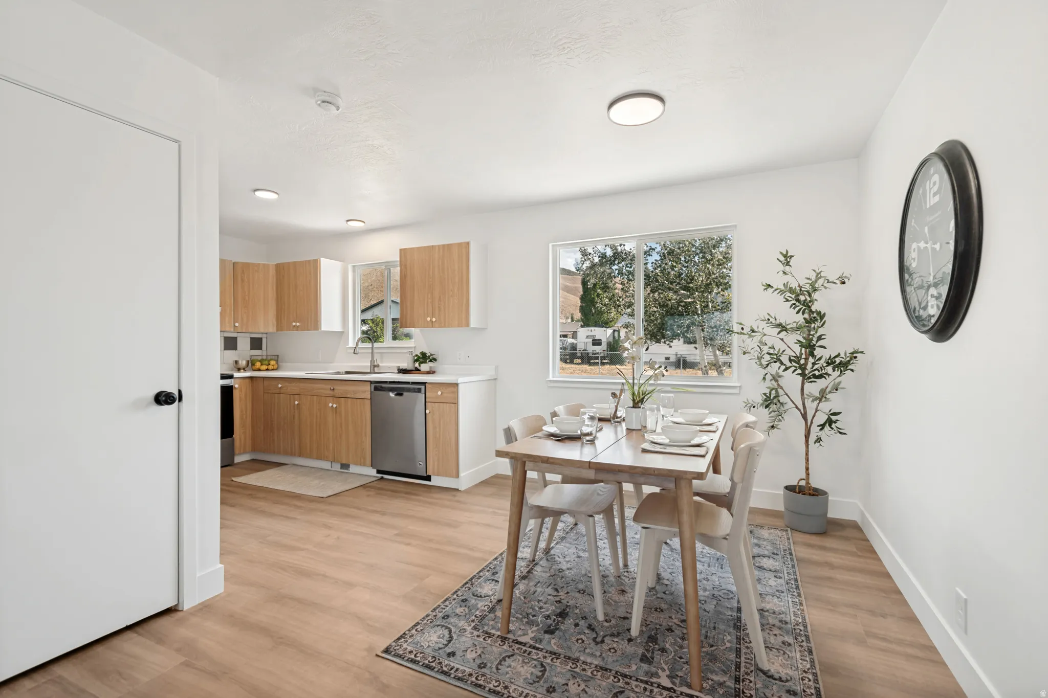 Open-concept kitchen and dining area featuring wood-finish flooring, white walls, and recessed lighting