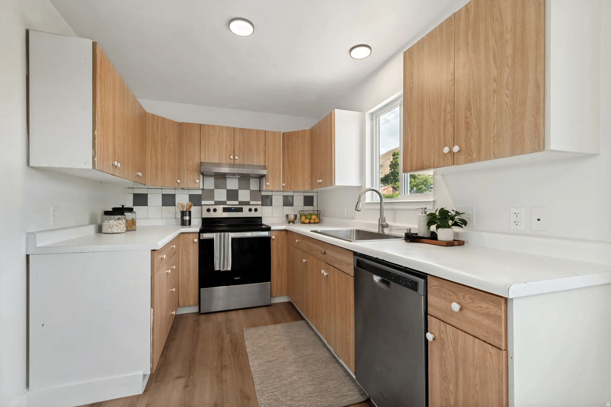 U-shaped kitchen featuring wood-finish cabinetry, white countertops, and wood-finish flooring