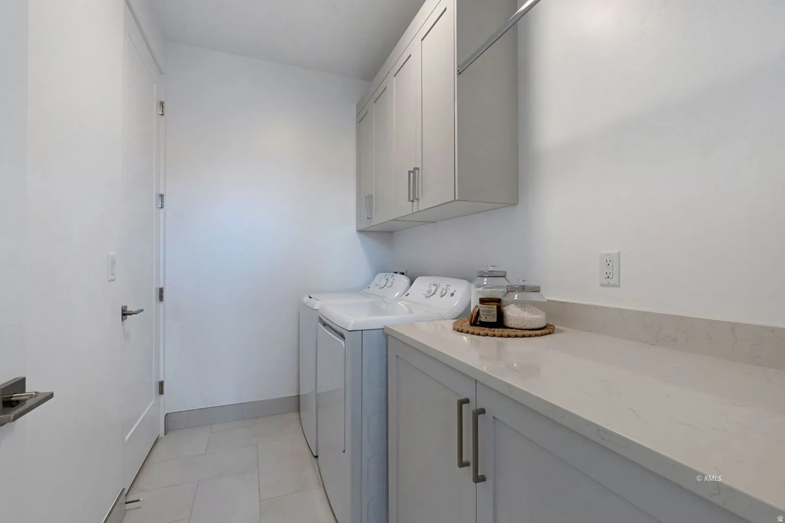 Laundry area featuring light gray cabinetry, a light-toned countertop, and tile flooring