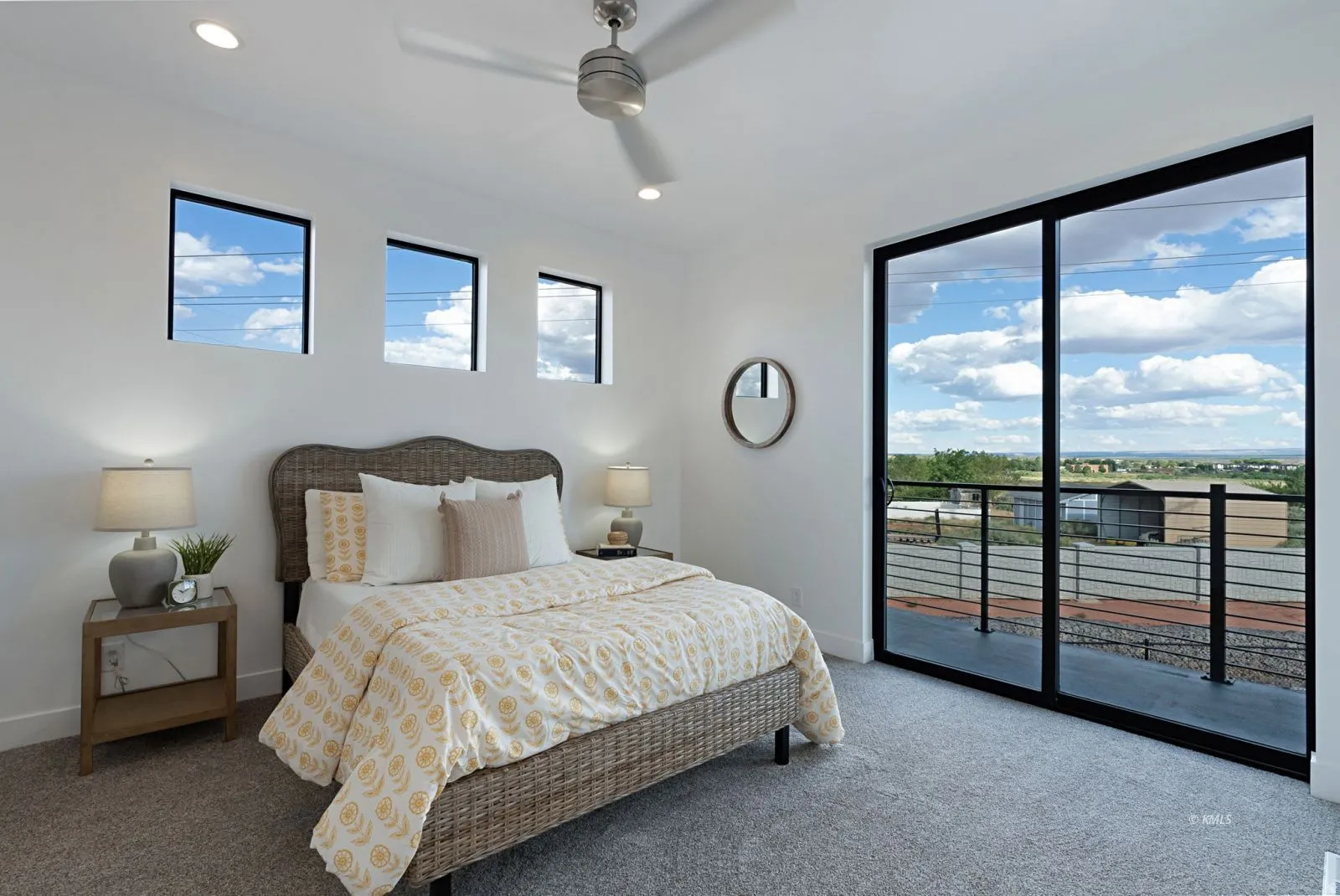 Spacious bedroom featuring a full wall of sliding glass doors opening to an exterior balcony with metal railings