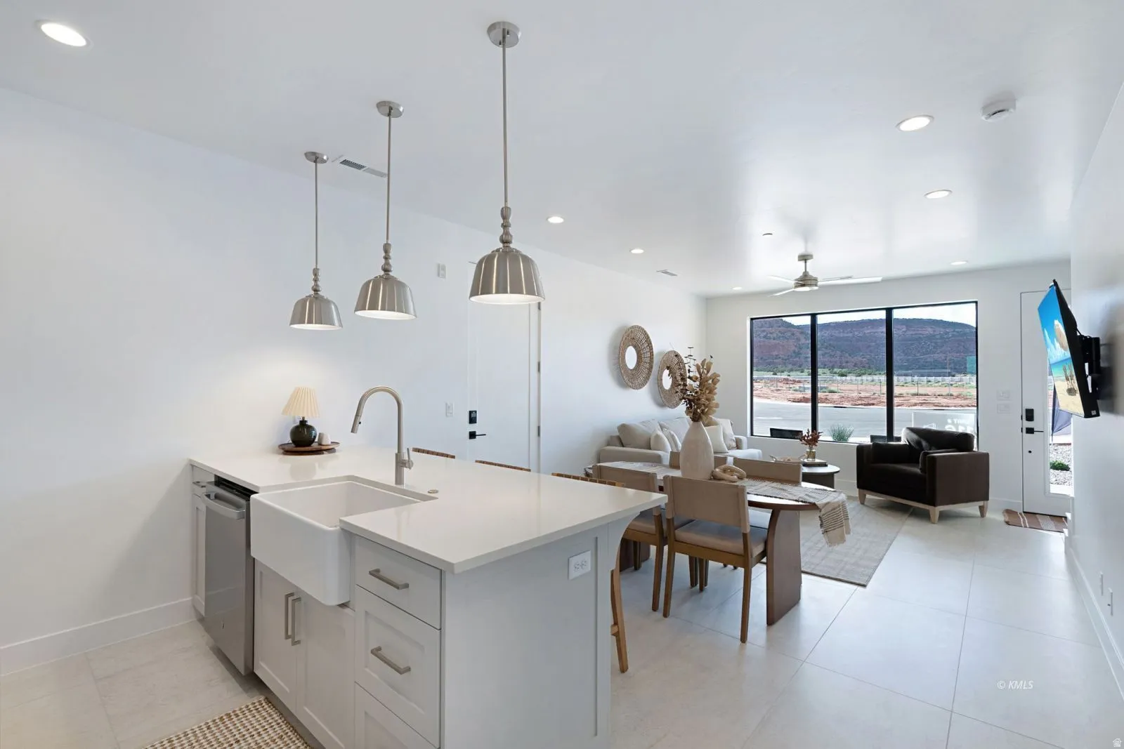 Open-concept living area featuring a kitchen island with a farmhouse sink, stainless steel dishwasher, and pendant lighting