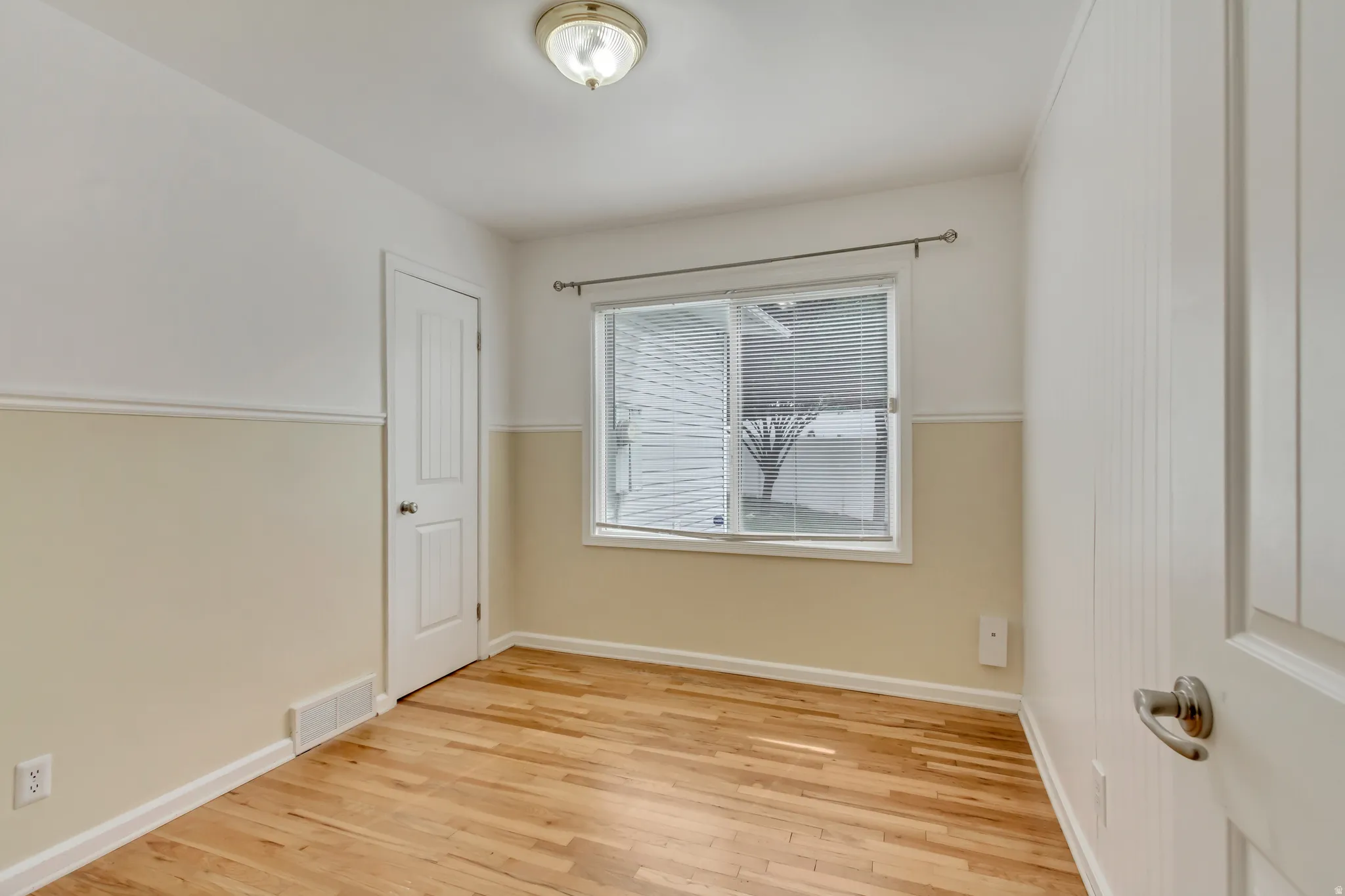 Bedroom featuring wood-finish flooring, a double-hung window, and a paneled door