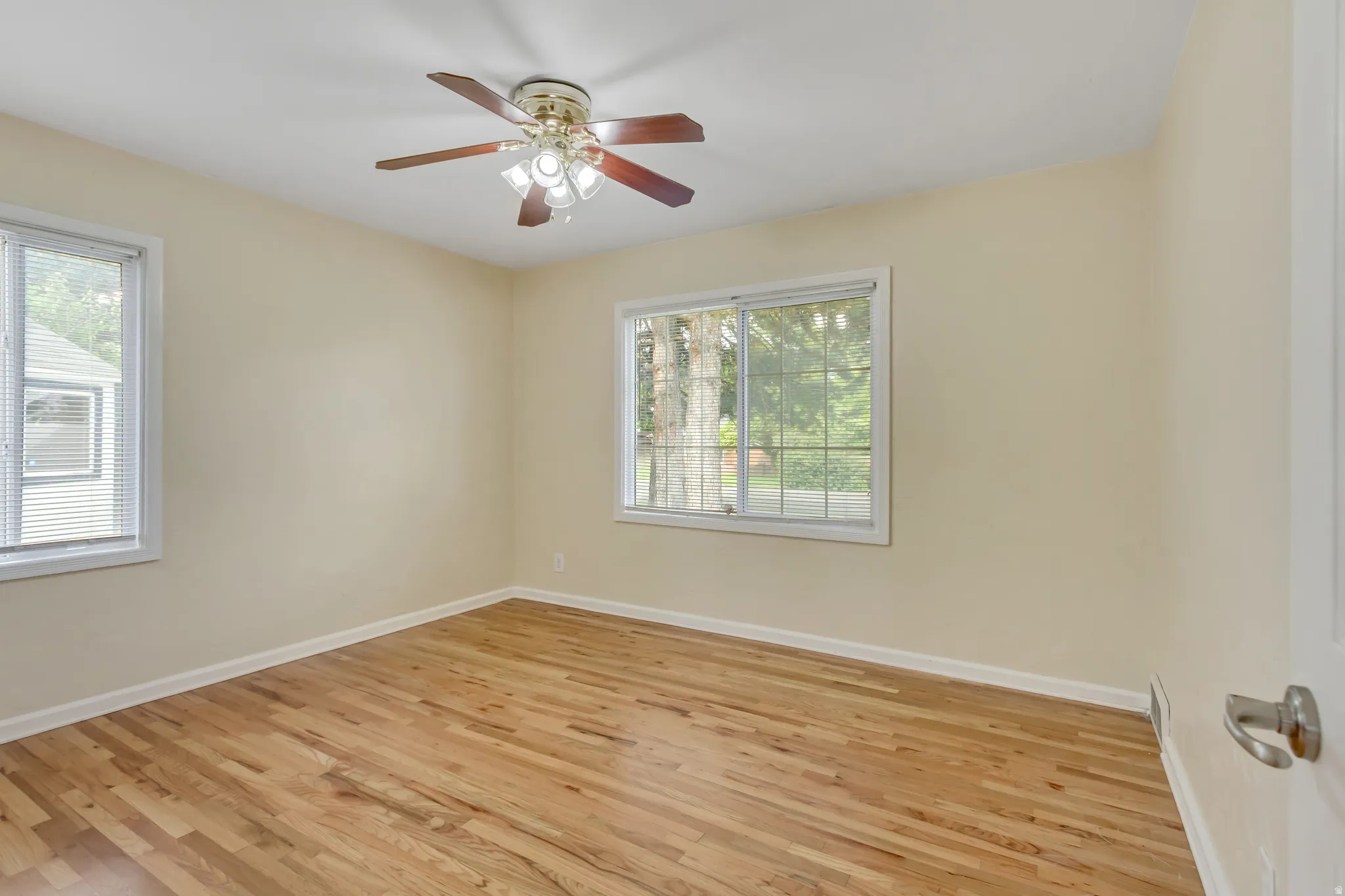 Light-filled room featuring wood-finish flooring, neutral wall tones, and white trim
