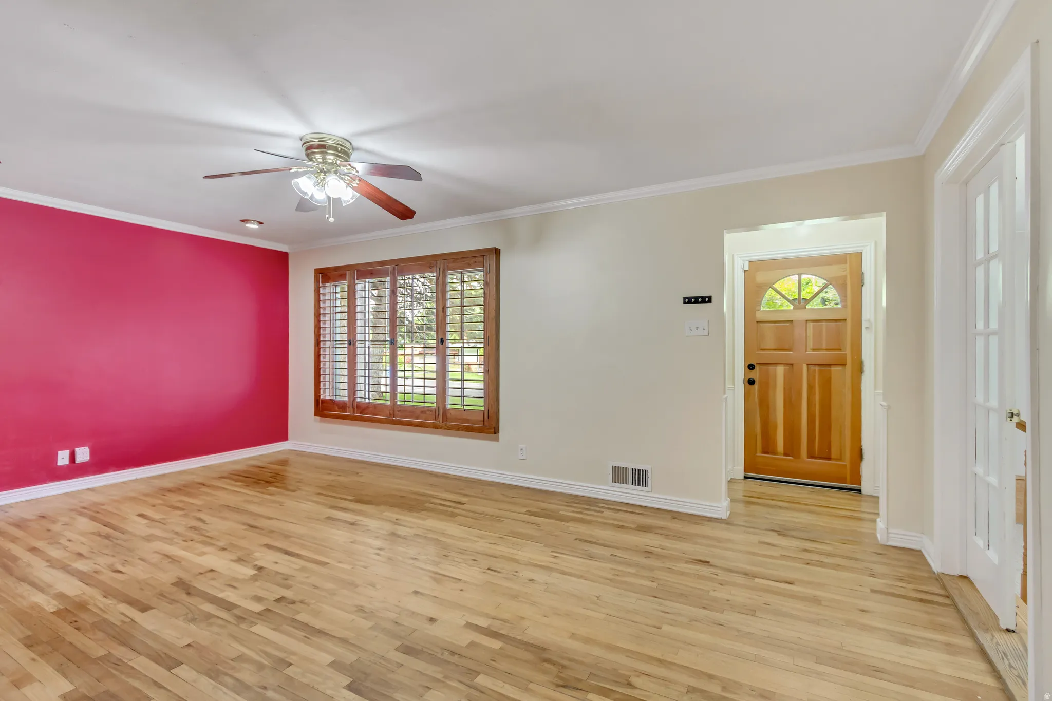 Hardwood-finish flooring throughout, featuring a natural wood entry door with an arched window