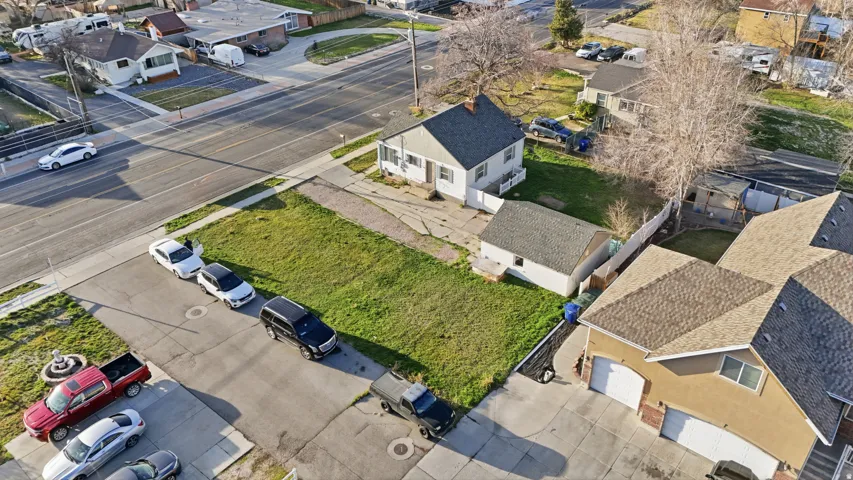 Corner lot featuring a single-story home with a light-colored exterior, a detached garage, and an expansive grassy area