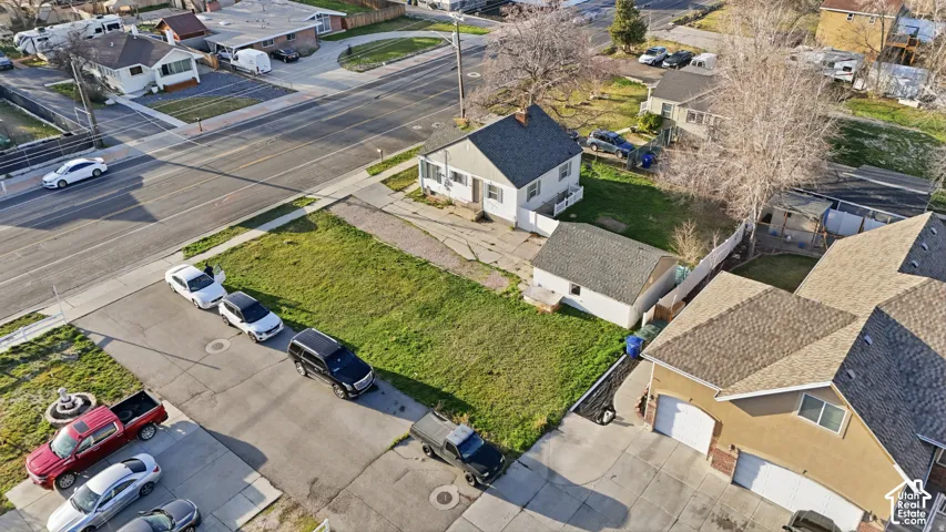 Corner lot featuring a single-story home with a light-colored exterior, a detached garage, and an expansive grassy area