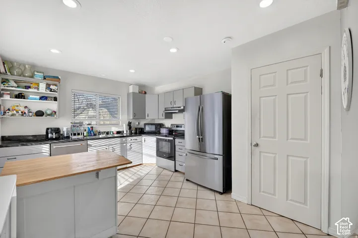 Kitchen featuring an island with a wood countertop, tile flooring, recessed lighting, and stainless steel appliances