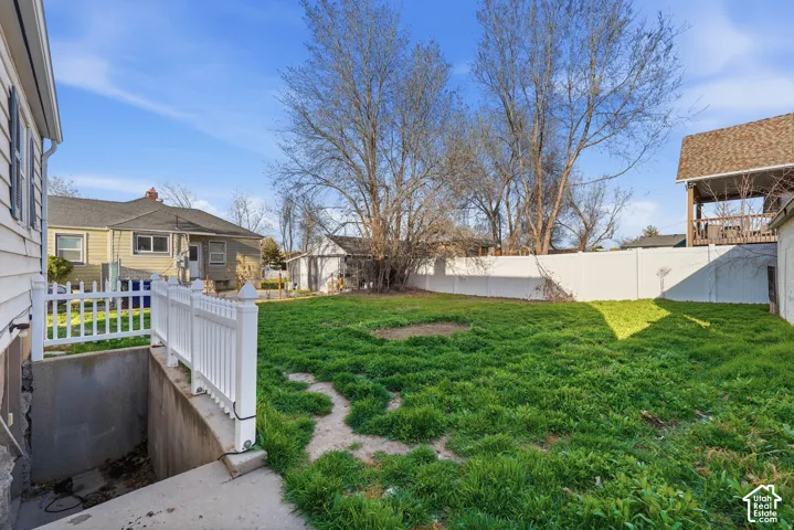 Expansive backyard with a level lawn, secured by a white privacy fence