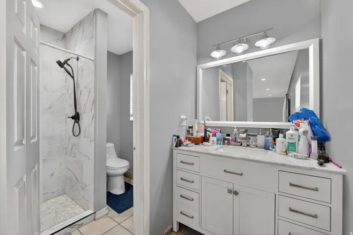 Bathroom featuring a white vanity with extensive storage, a large framed mirror, and a three-light fixture